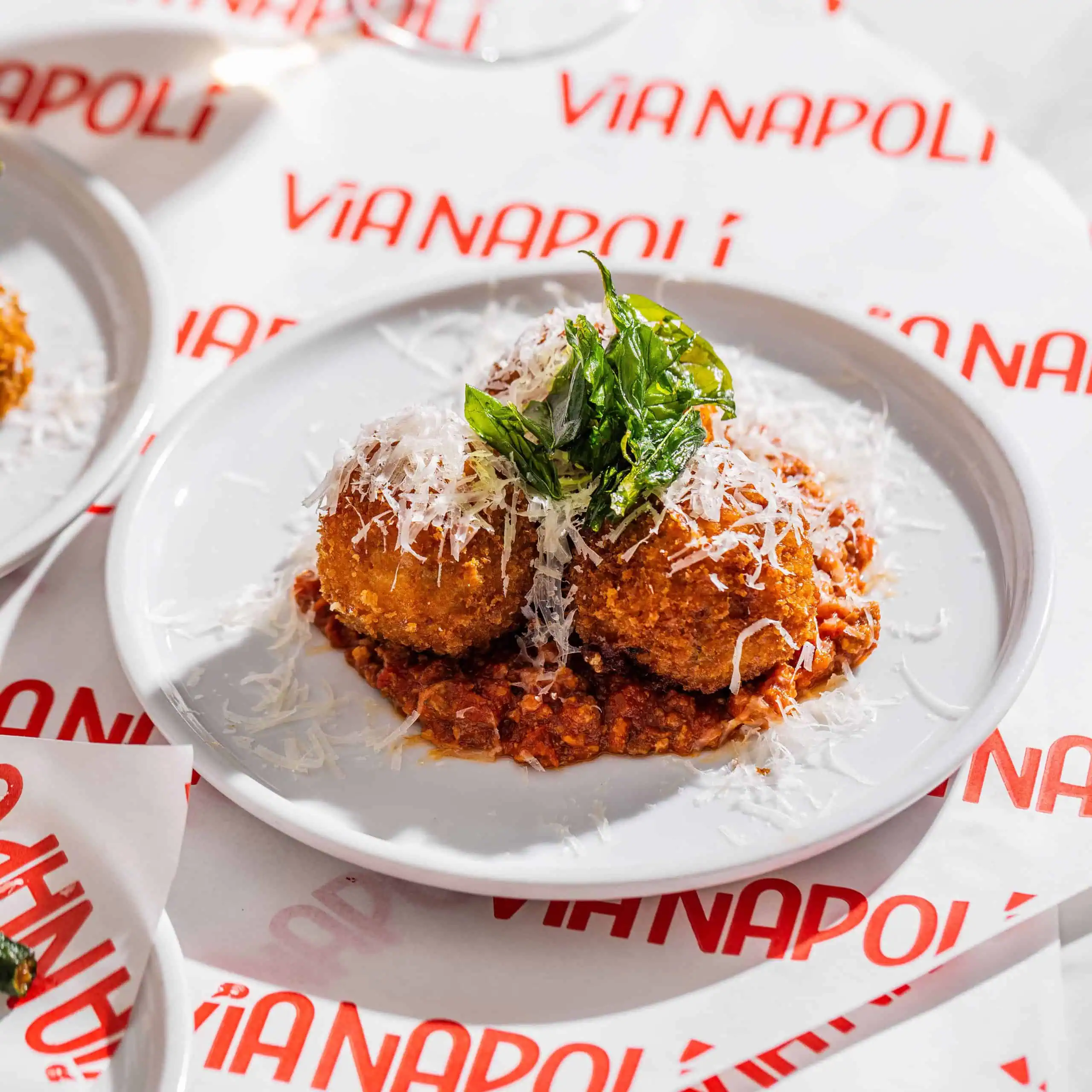 Golden arancini served on rich veal and pork Bolognese with peas and buffalo mozzarella at Via Napoli