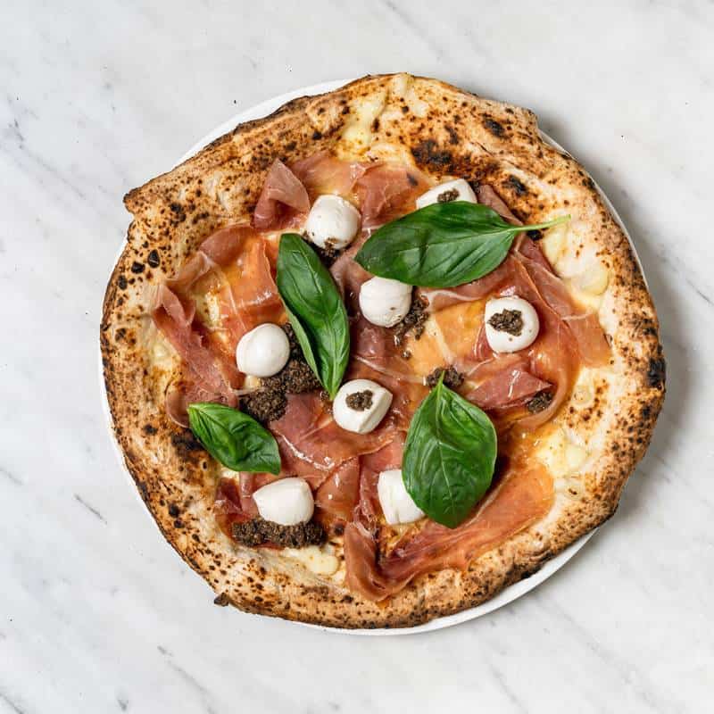 Chiara pizza topped with fior di latte, creamy buffalo bocconcini, prosciutto, and aromatic black truffle
