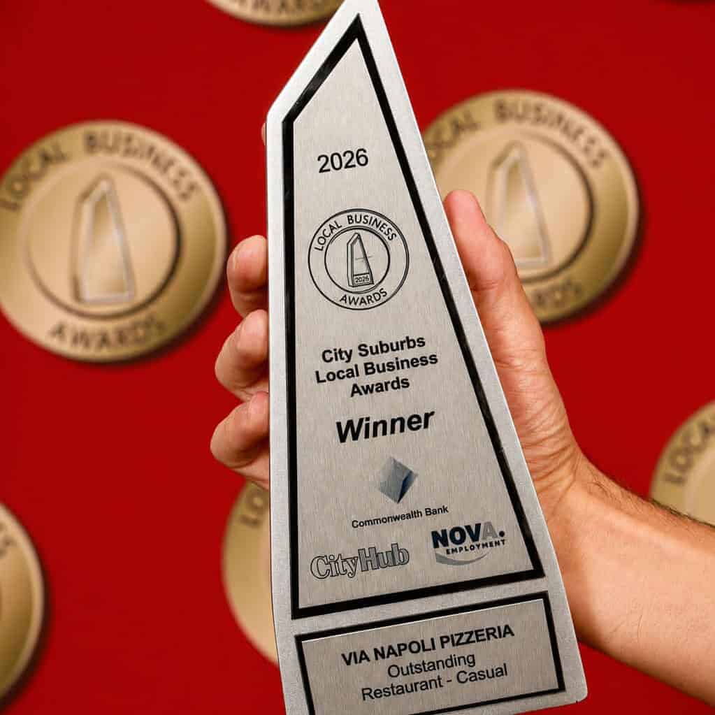 Hand holding a City Suburbs Local Business Awards 2026 winner trophy awarded to Via Napoli Pizzeria for Outstanding Restaurant (Casual).