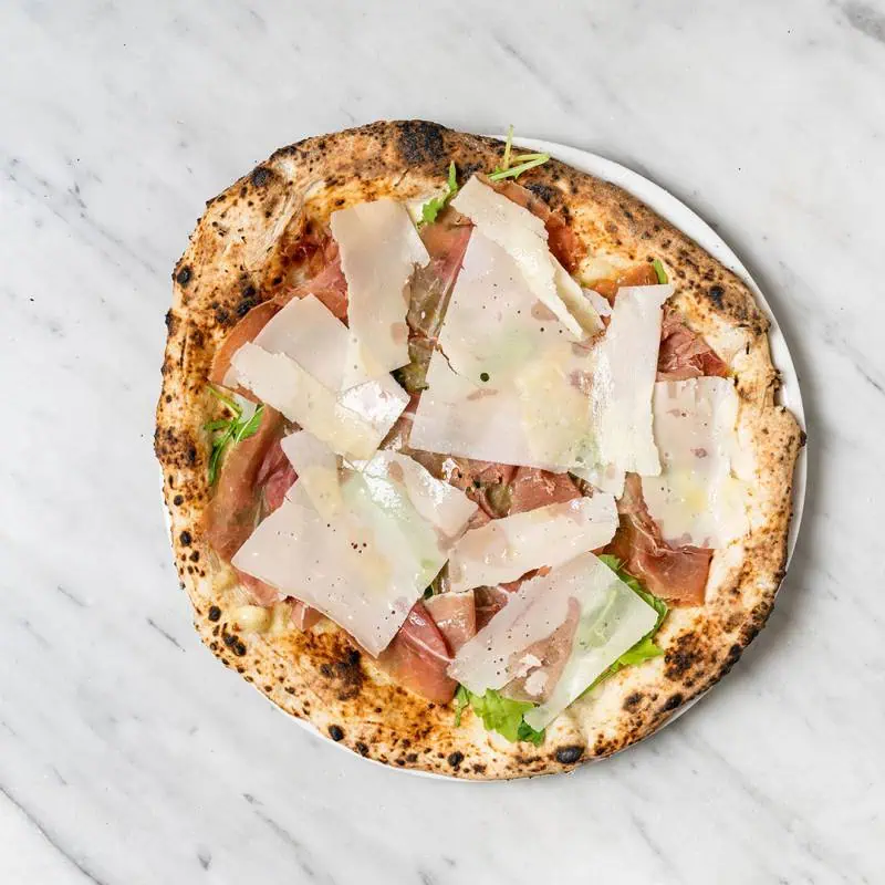 Crudo e Rucola pizza topped with fior di latte, San Daniele prosciutto, fresh rocket, and shaved Parmesan cheese