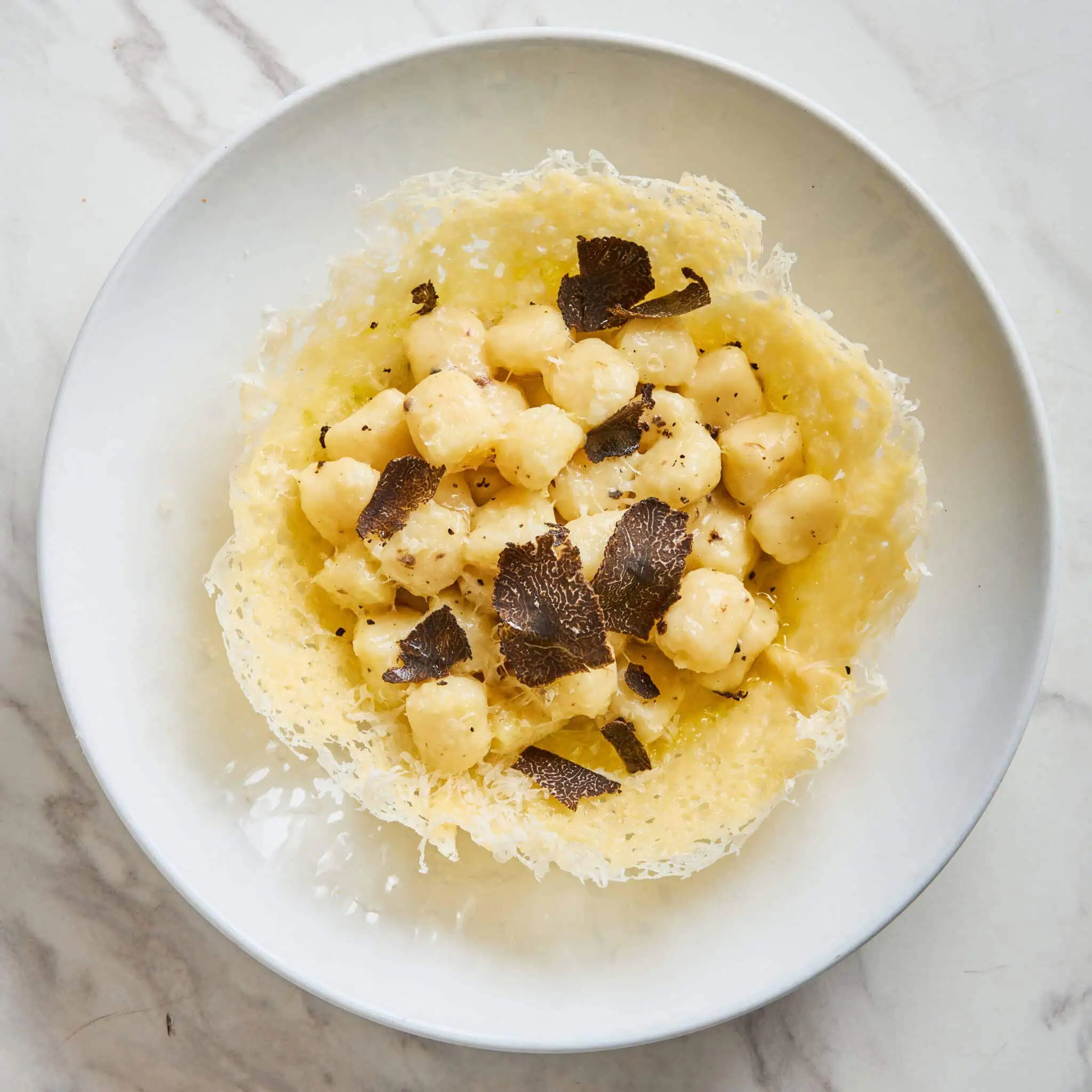 Homemade potato gnocchi coated in a creamy four-cheese sauce of gorgonzola, Parmigiano Reggiano, pecorino romano, and taleggio, topped with shaved truffle and served in a crisp Parmigiano cheese basket