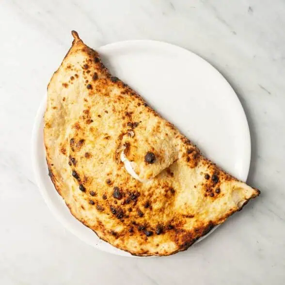 Folded Maradona pizza filled with fior di latte, buffalo ricotta, Neapolitan salame, black pepper, burrata, and fresh basil