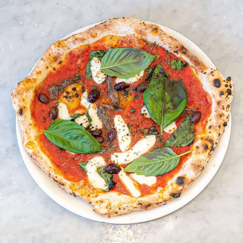 Napoletana pizza topped with fior di latte, anchovies, capers, black olives, San Marzano tomato, oregano, and fresh basil