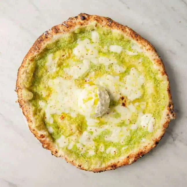 Nerano pizza topped with Fior di Latte, zucchini purée, creamy burrata cheese, Grana Padano DOP, fresh basil, and EVOO at Via Napoli