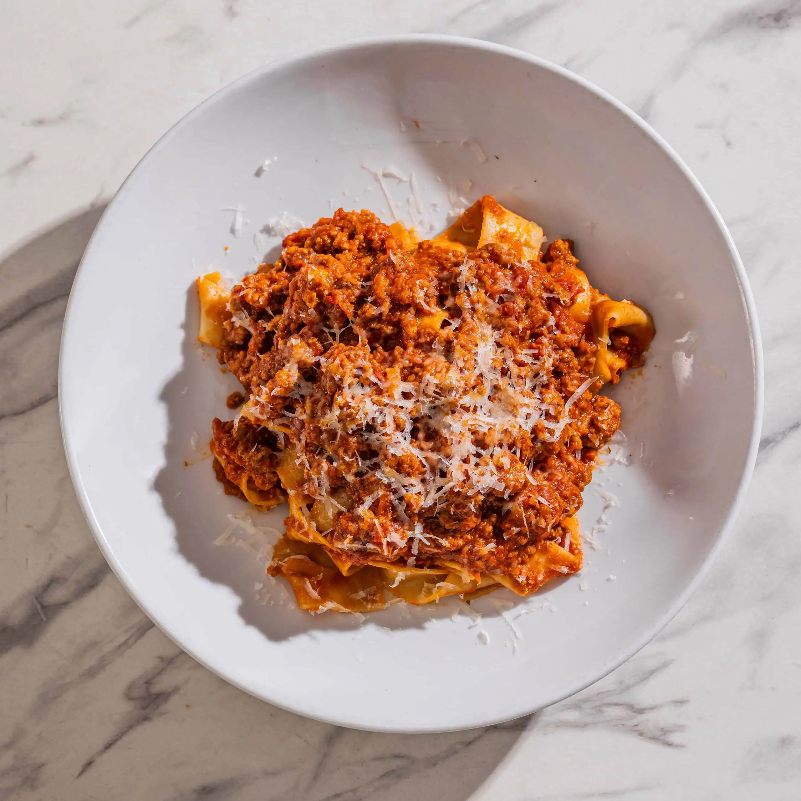 Pappardelle pasta coated in rich Bolognese ragu, topped with freshly grated Parmigiano Reggiano