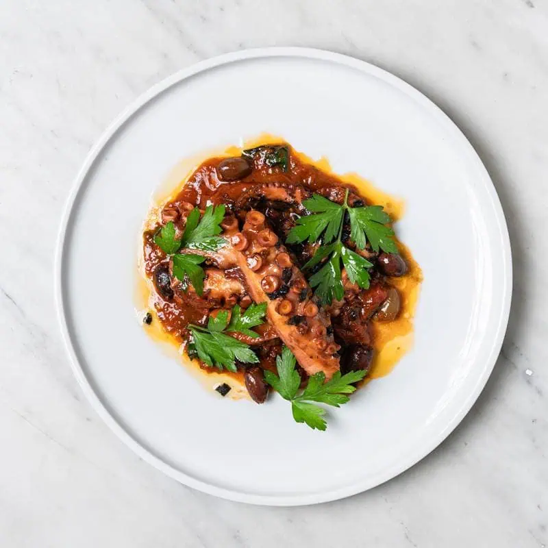 Polpo alla Luciana dish featuring tender Western Australian octopus tentacle with capers, cherry tomatoes, and olives