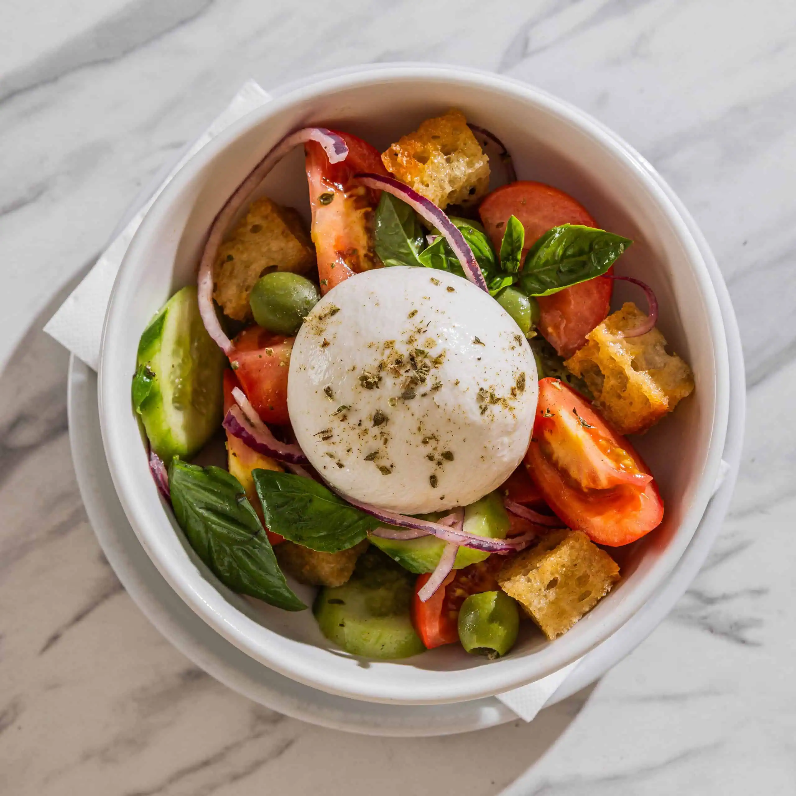 Puverella salad with vine-ripened tomatoes, cucumber, green olives, Spanish onions, croutons, burrata cheese, oregano, basil, and extra virgin olive oil at Via Napoli