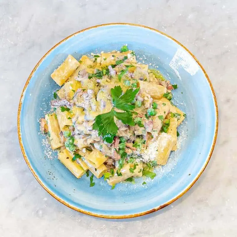 Homemade rigatoni pasta in a creamy sauce with mushrooms, crispy Prosciutto di Parma, black pepper, and 36-month aged Parmigiano Reggiano