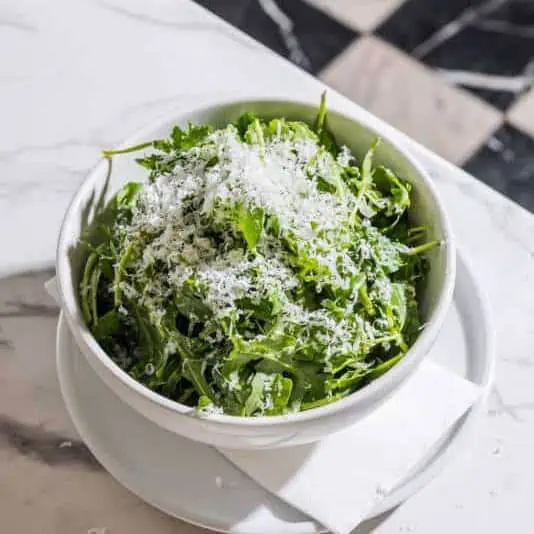Fresh rocket salad topped with shaved Grana Padano DOP and drizzled with honey truffle dressing at Via Napoli