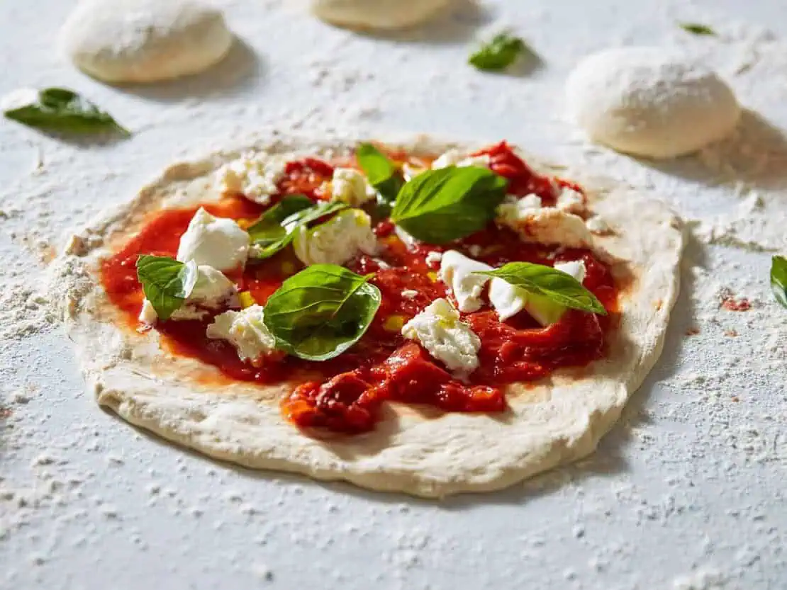 Uncooked Margherita pizza preparation fresh dough and basil