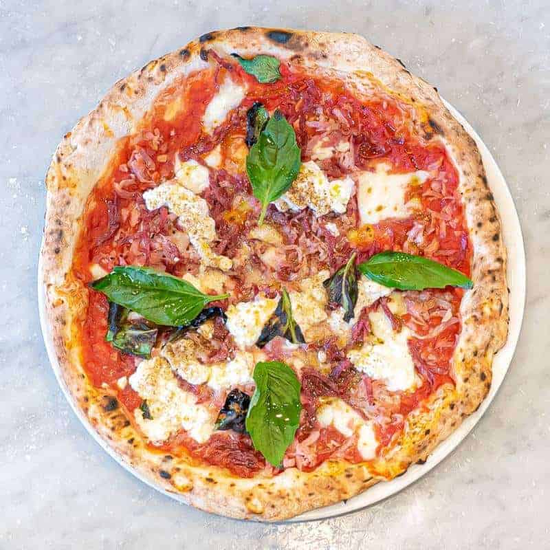 Vesuvio pizza topped with Solania San Marzano tomatoes, Fior di Latte, buffalo ricotta, double smoked shoulder ham, mild Neapolitan salami, pepper, basil, and EVOO at Via Napoli