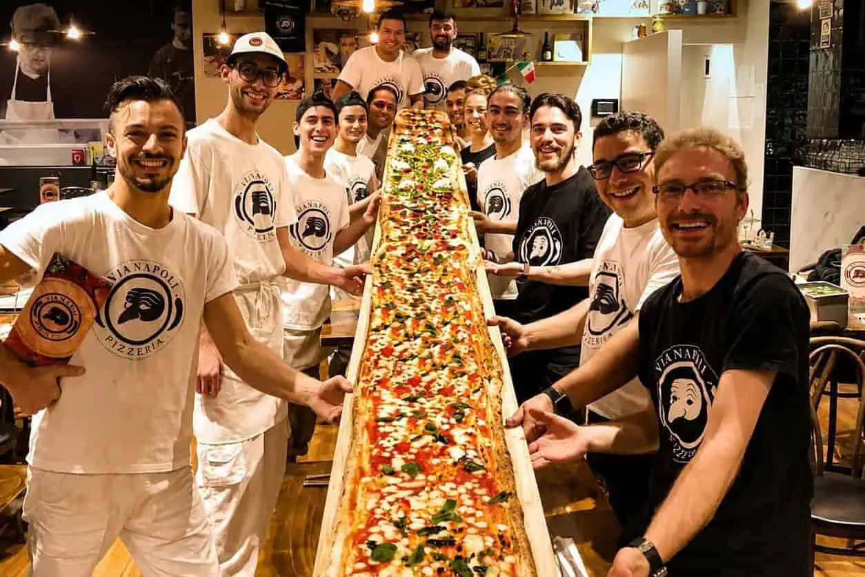 Group of Via Napoli staff and diners holding a 5-metre long giant pizza during the Via Napoli pizza challenge inside the restaurant