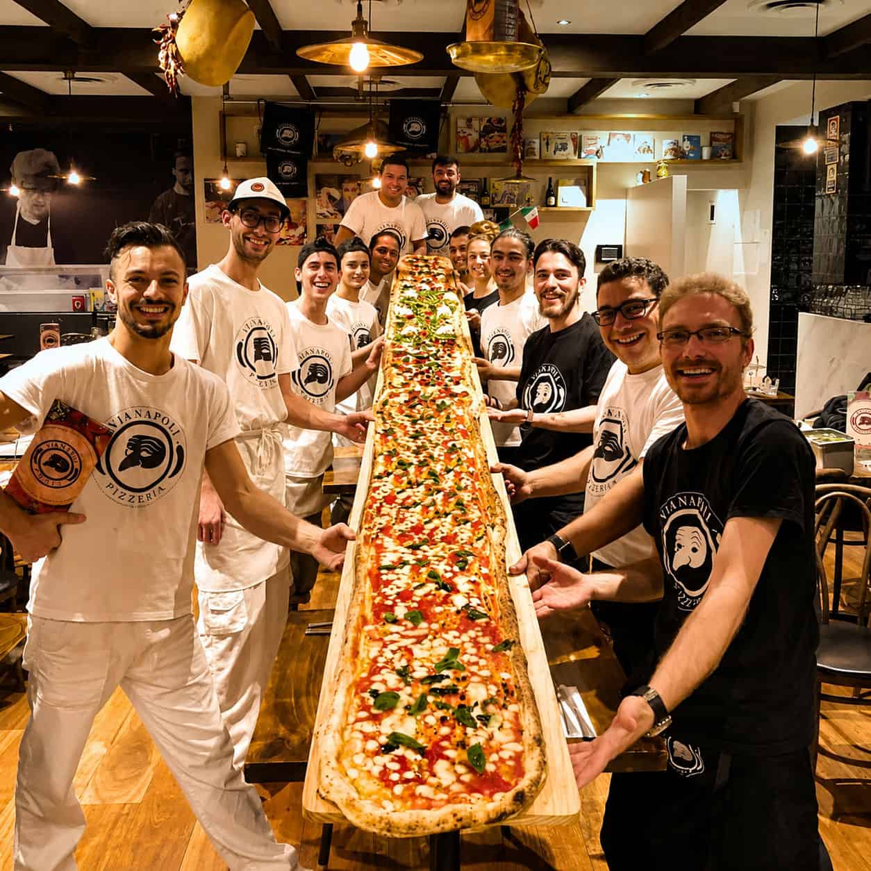 Group of Via Napoli staff and diners holding a 5-metre long giant pizza during the Via Napoli pizza challenge inside the restaurant