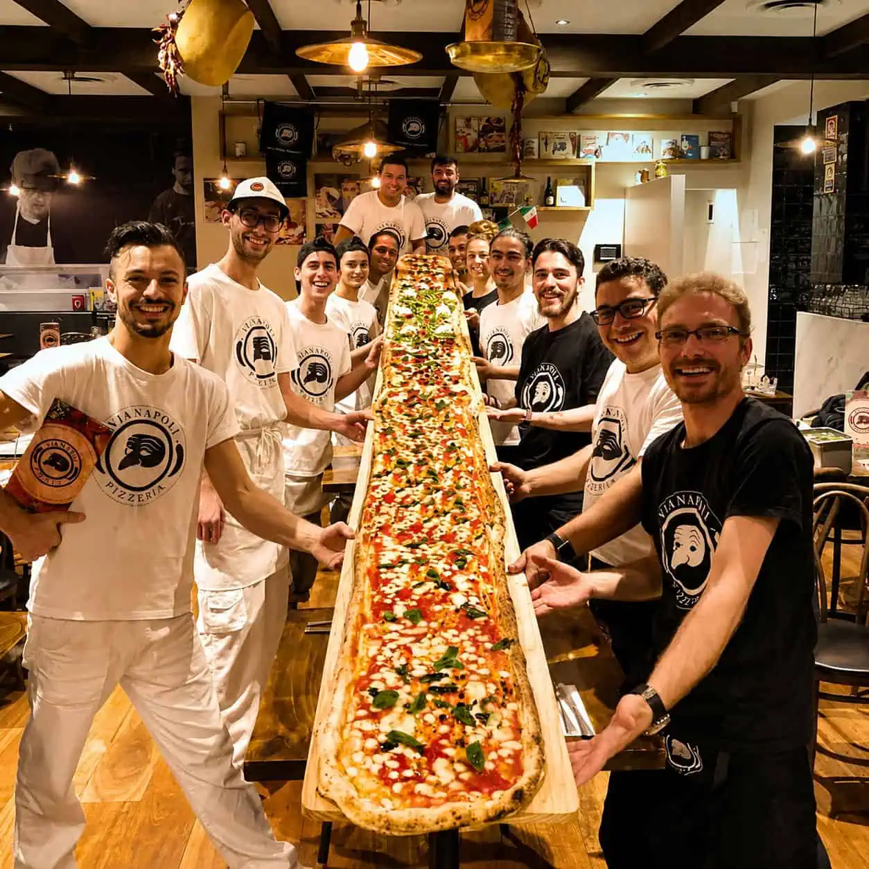 Group of Via Napoli staff and diners holding a 5-metre long giant pizza during the Via Napoli pizza challenge inside the restaurant