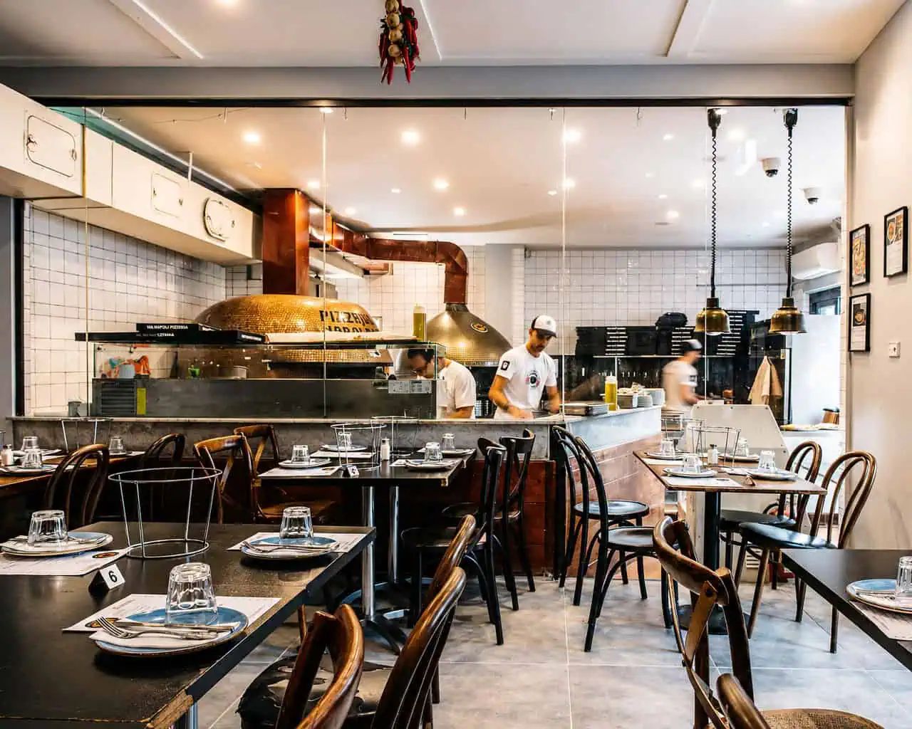 Interior of Via Napoli Pizzeria in Lane Cove featuring wood-fired pizza oven and dining tables