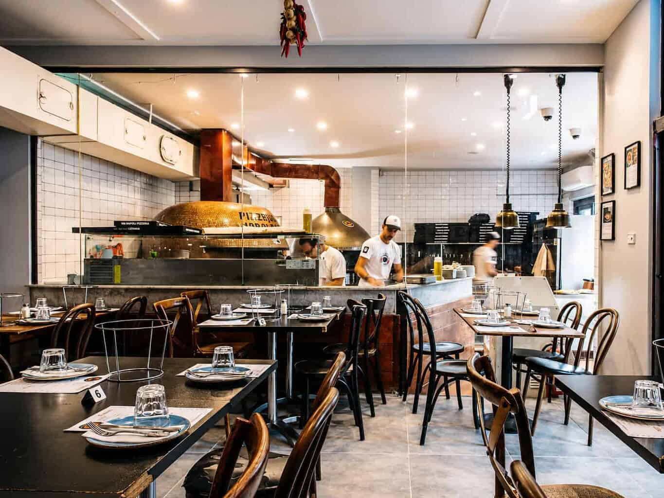 Interior of Via Napoli Pizzeria in Lane Cove featuring wood-fired pizza oven and dining tables